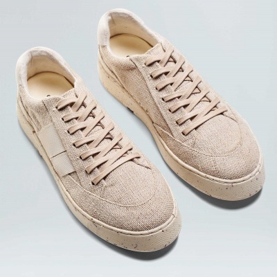 Par de sapatilhas bege com textura de tecido e atacadores em fundo claro
