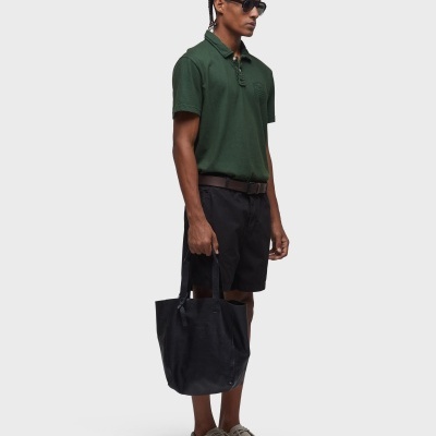 Homem vestido com camisola polo verde, calções pretos e mala tote preta