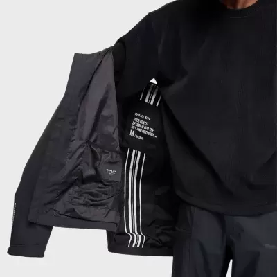 Casaco preto OSKLEN com etiquetas internas e bolso visível, usado por homem em camisola preta