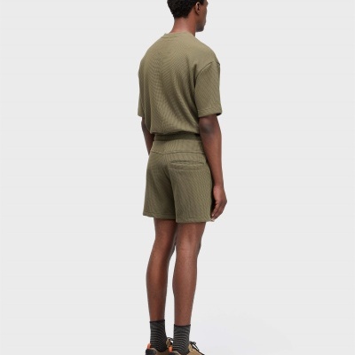 Homem com conjunto verde-oliva e sapatos bege visto de costas