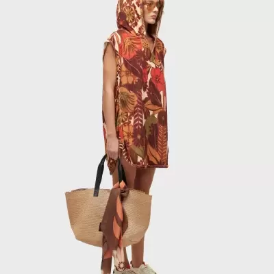 Poncho com capuz floral e saco de palha com lenço, sapatos brancos e óculos de sol