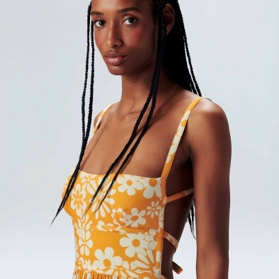 Vestido amarelo com flores brancas e alças finas usado por modelo