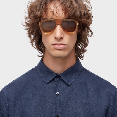 Homem com camisa azul e óculos de sol castanhos.