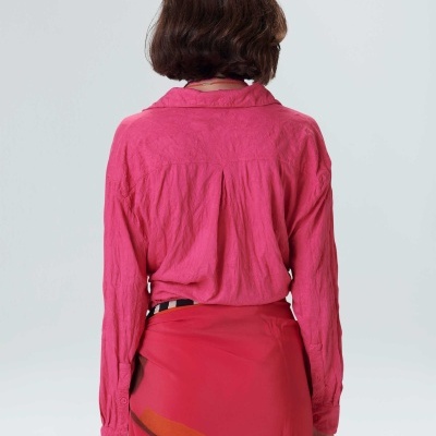 Pessoa com camisa rosa e saia vermelha com padrão geométrico vista de costas