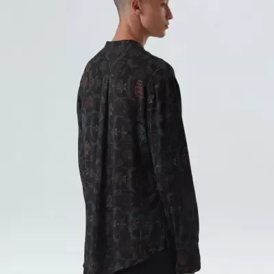 Camisa preta com padrão abstrato em várias cores utilizada por modelo de perfil
