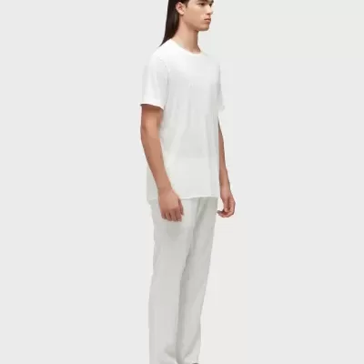 Homem com roupa branca e chinelos em fundo cinza claro