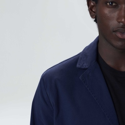 Pessoa a usar casaco azul escuro e t-shirt preta com fundo cinza claro