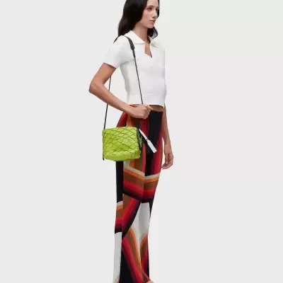 Mulher com roupa colorida e mala verde com textura