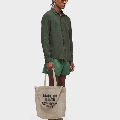 Homem com camisa verde, calções verdes e sacola bege com texto