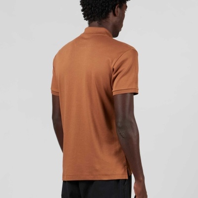 Homem de costas a usar t-shirt polo castanho alaranjado e calças pretas