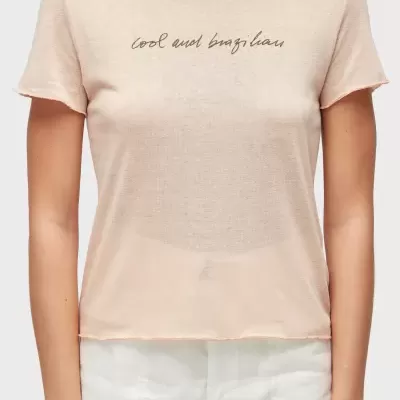 T-shirt bege claro com texto cool and brazilian usada com calças brancas