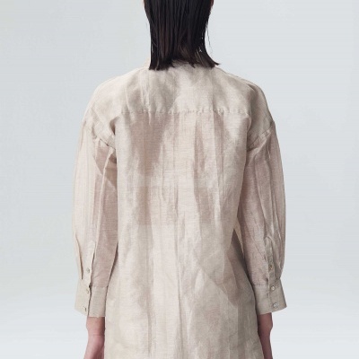Camisa comprida bege claro vista de costas em fundo cinzento claro