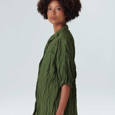 Mulher com camisa verde enrugada de manga curta vista de perfil