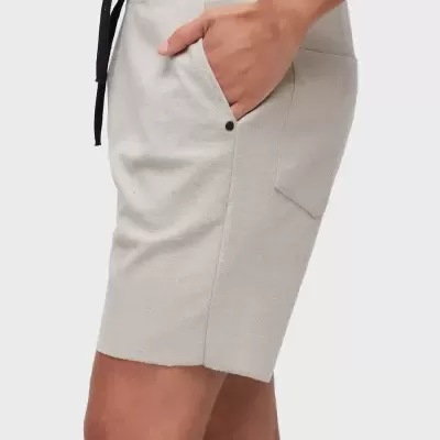 Calções bege claro com bolso e cordão preto, detalhes próximos da cintura numa imagem de estúdio.