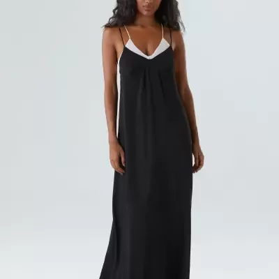 Vestido longo preto com detalhe branco no decote usado por modelo com fundo branco