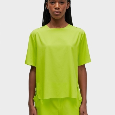 Pessoa com roupa verde-limão sobre fundo cinza-claro.