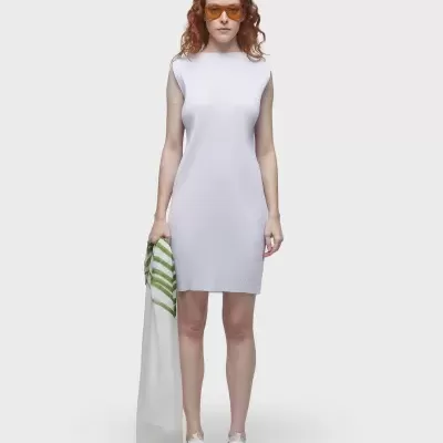 Mulher de vestido branco justo sem mangas com óculos laranja segurando lenço branco com riscas verdes