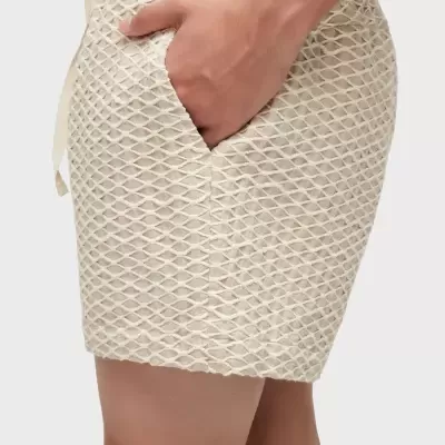 Saia curta bege com padrão de rede em relevo e bolso lateral