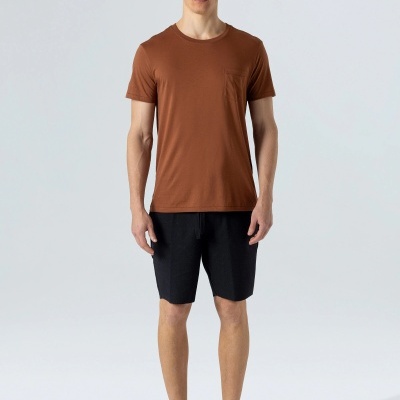 Homem com t-shirt castanha, calções pretos e sapatos pretos