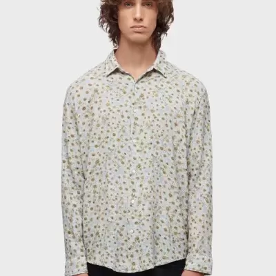 Homem com camisa floral bege e azul claro e calças pretas com fundo branco
