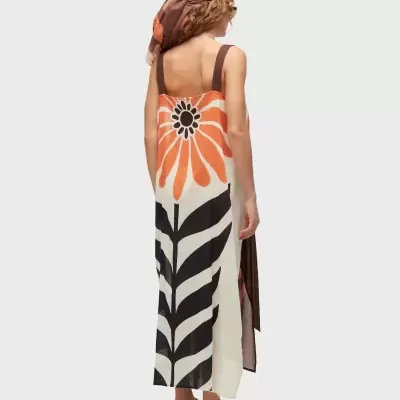 Vestido comprido com flor laranja grande e folhas pretas, lenço na cabeça e sandálias castanhas