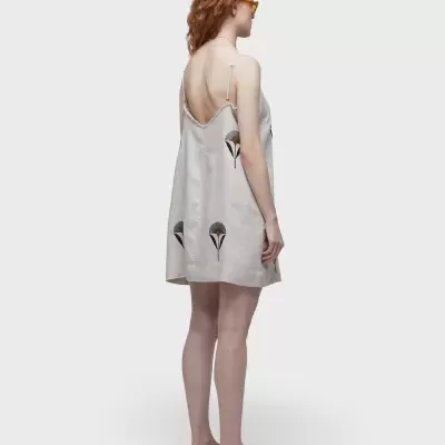 Vestido cinza claro com padrão floral usado por mulher de lado, fundo branco.
