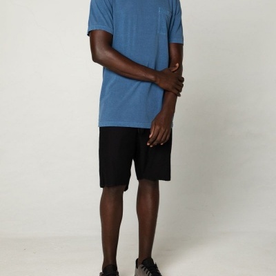 Homem de pé com t-shirt azul, calções pretos e sapatilhas cinzentas