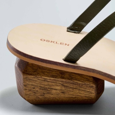 Sandália de madeira com tiras de couro verde e marca OSKLEN visível na palmilha