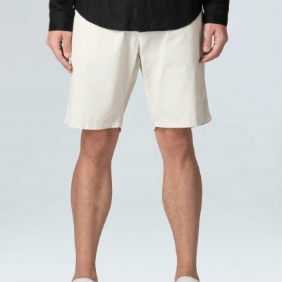 Homem com bermudas brancas, camisa preta e sapatos brancos