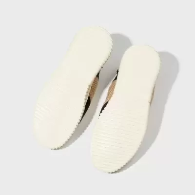 Solados brancos de sapatos com textura, parte superior castanha, preta e bege num fundo cinza claro