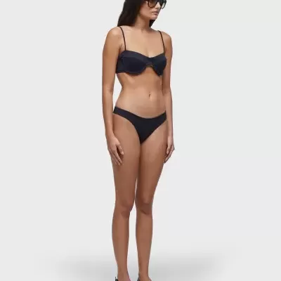 Mulher com biquíni preto de dois pedaços em fundo branco