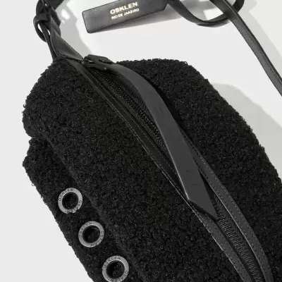 Mala preta felpuda com detalhes em couro e etiqueta Osklen Rio de Janeiro