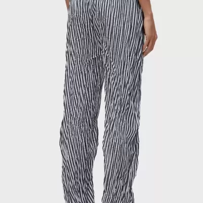 Calças largas riscas pretas e brancas com cintura elástica e sandálias pretas.