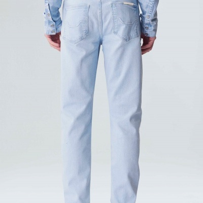 Calças de ganga azuis claras vistas de trás, usadas com camisa azul clara e sapatos brancos.