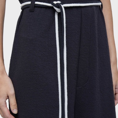 Roupa preta com cinto de corda branco e preto amarrado na cintura