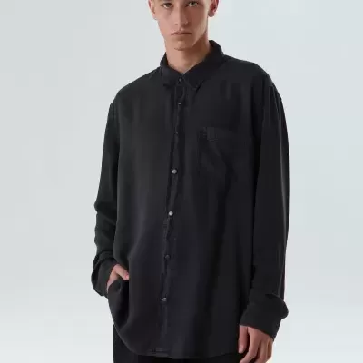 Homem a usar camisa preta de manga comprida com bolso no peito