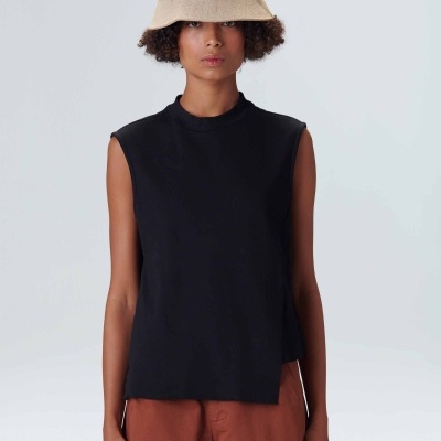 Modelo com regata preta sem mangas, calças castanhas e chapéu bucket bege