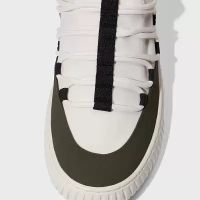 Ténis branco com biqueira verde-oliva e faixa preta vertical nos atacadores