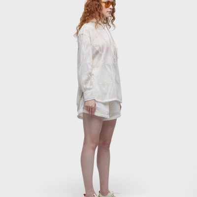 Mulher ruiva de óculos usando camisa branca e calções brancos com ténis