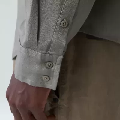 Punho de camisa cinza claro com botões e calças castanhas claras