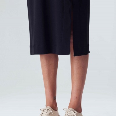 Saia preta com fenda lateral e ténis bege claro com atacadores