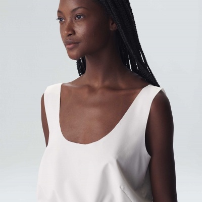 Mulher com top branco e calças castanhas