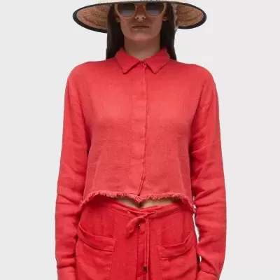 Modelo a usar blusa de malha vermelha e saia vermelha, chapéu de palha e óculos de sol