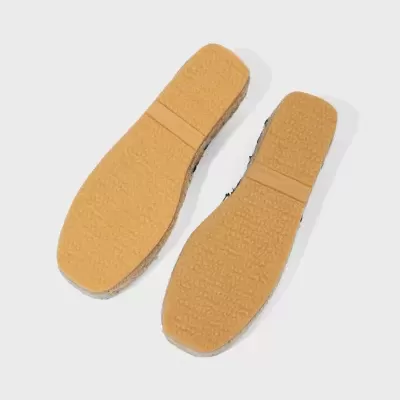 Solas de calçado castanho claro com padrão texturizado.