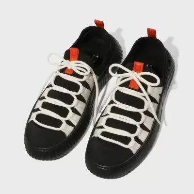 Par de ténis desportivos preto e branco com detalhes laranja