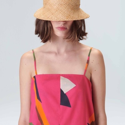 Mulher com chapéu de palha e vestido rosa com padrão geométrico