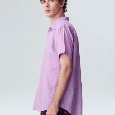 Camisa lilás de manga curta com bolso, usada com calções pretos com padrão laranja