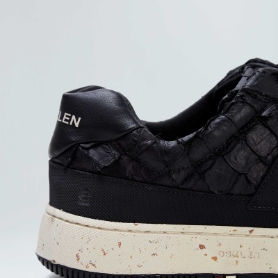 Sapato desportivo preto com textura tipo escamas e sola branca manchada