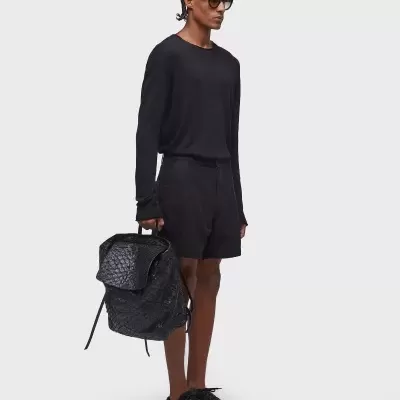 Homem vestido de preto com mochila preta e óculos escuros