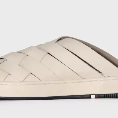 Chinelo mule creme claro com tiras entrelaçadas e sola branca com detalhe tricolor